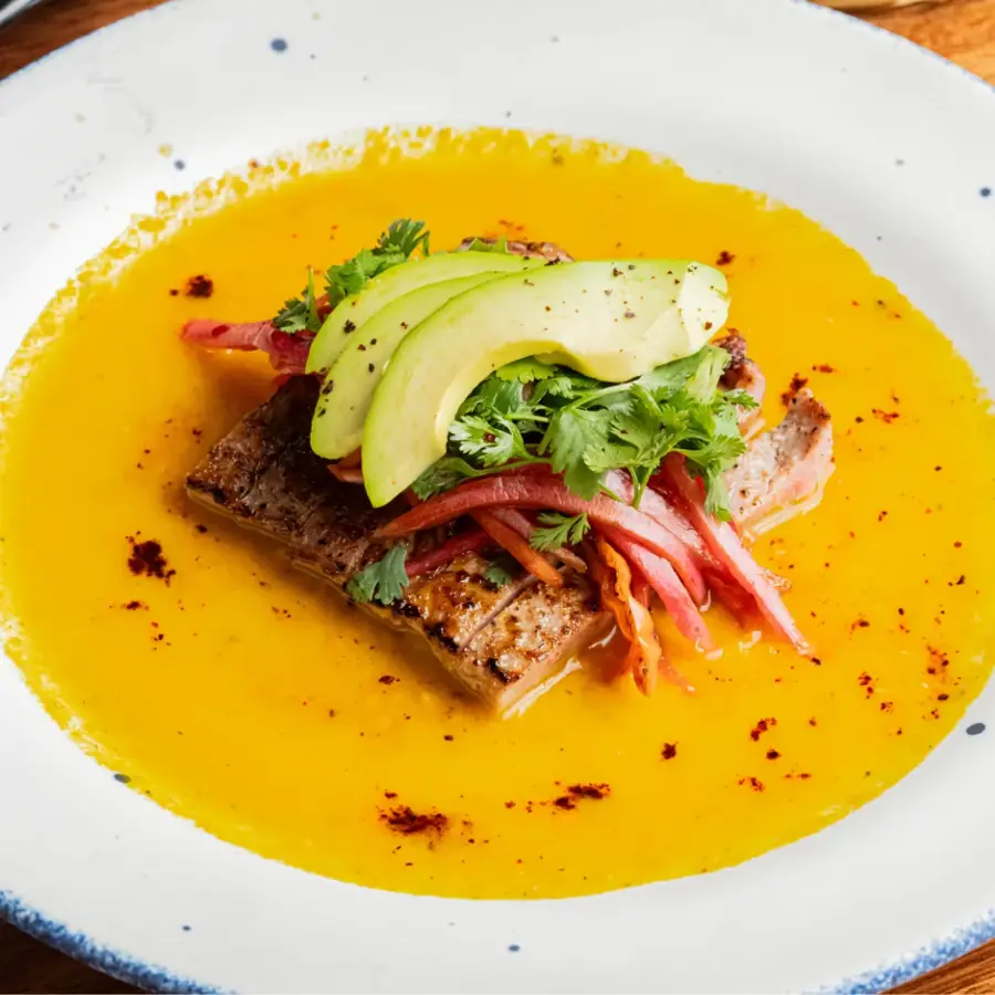 Pescado con aguacate y verduras sobre salsa amarilla